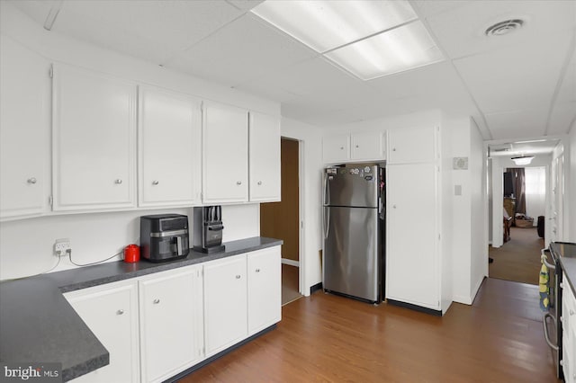 kitchen featuring white cabinetry, a drop ceiling, stainless steel fridge, and dark hardwood / wood-style flooring