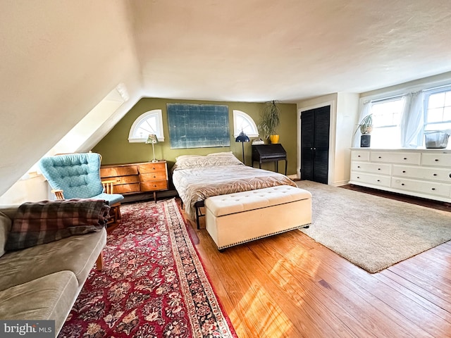 bedroom featuring multiple windows, vaulted ceiling, and hardwood / wood-style floors