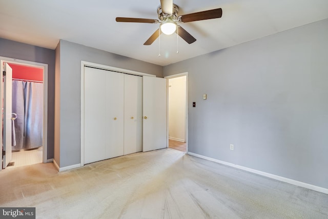 unfurnished bedroom featuring ceiling fan, light colored carpet, ensuite bath, and a closet