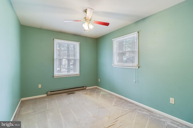 spare room featuring a baseboard heating unit, ceiling fan, a healthy amount of sunlight, and carpet flooring