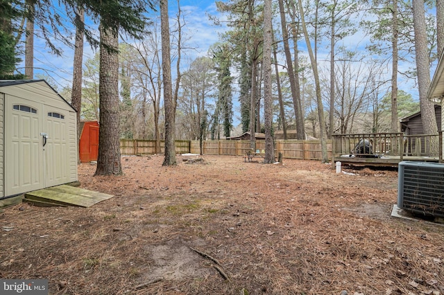 view of yard featuring a deck, central AC unit, and a shed