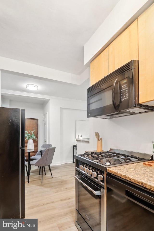 kitchen with light brown cabinets, light wood-type flooring, and black appliances