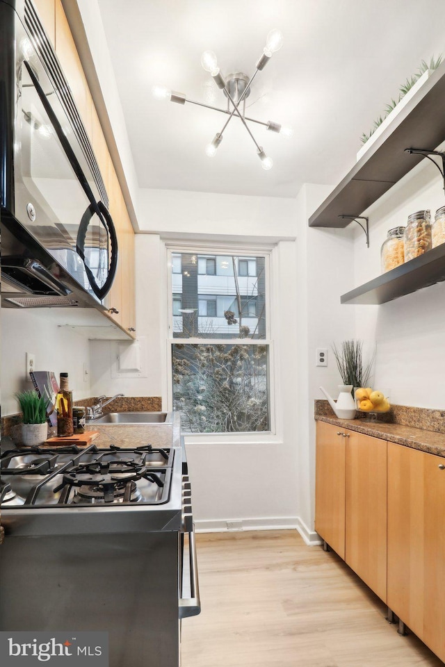 kitchen with cooktop, sink, light hardwood / wood-style flooring, and a notable chandelier