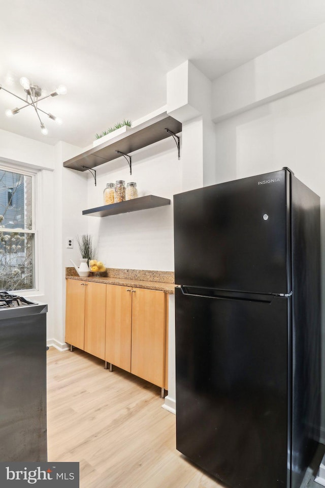 kitchen featuring light brown cabinetry, light hardwood / wood-style flooring, and black fridge