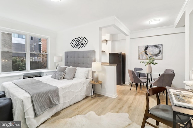 bedroom featuring black refrigerator, crown molding, and light hardwood / wood-style flooring