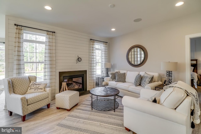 living room with a large fireplace, a wealth of natural light, and light hardwood / wood-style flooring