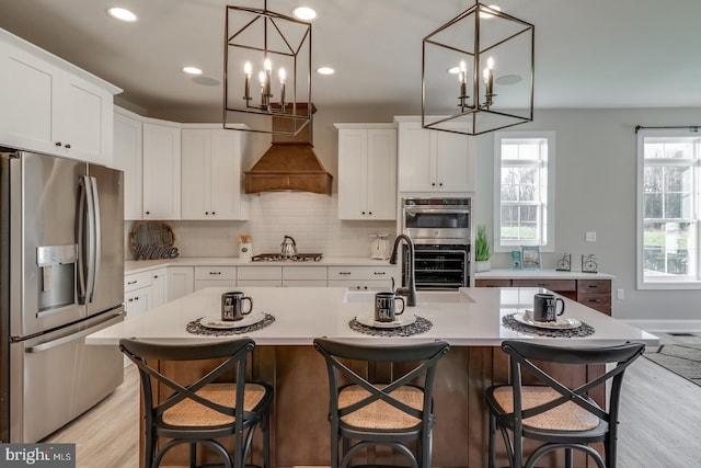 kitchen featuring stainless steel appliances, white cabinetry, and a center island with sink