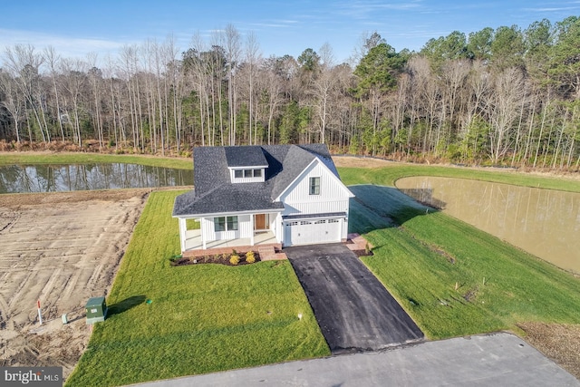 view of front of property with a water view, a garage, covered porch, and a front yard