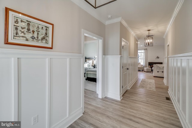 hall featuring a notable chandelier, ornamental molding, and light hardwood / wood-style floors