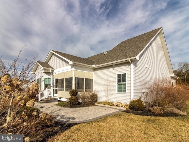 rear view of property with a sunroom, a yard, and a patio area