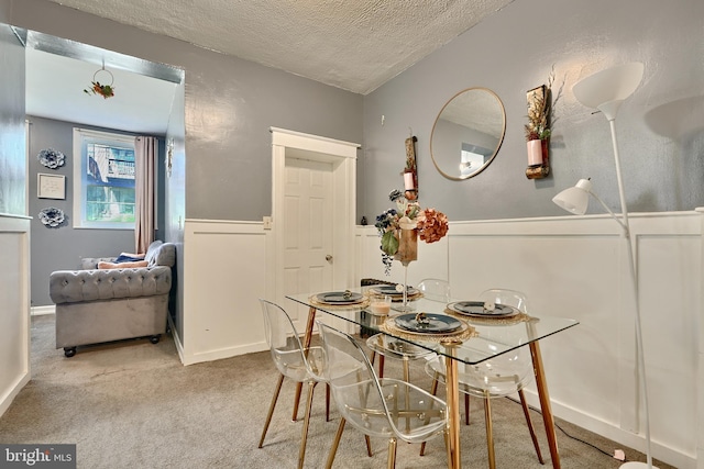 carpeted dining area with a textured ceiling