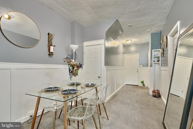 dining room featuring light colored carpet and a textured ceiling