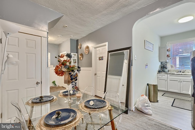 dining space featuring sink, light hardwood / wood-style flooring, and a textured ceiling