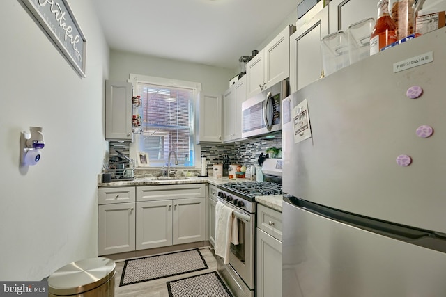 kitchen featuring white cabinetry, stainless steel appliances, light stone countertops, and sink