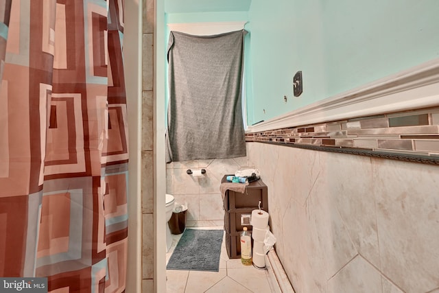 bathroom featuring tile patterned flooring, a shower, tile walls, and toilet