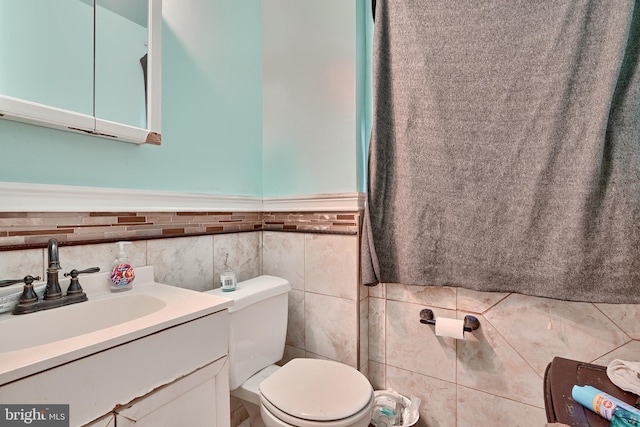 bathroom featuring vanity, tile walls, and toilet