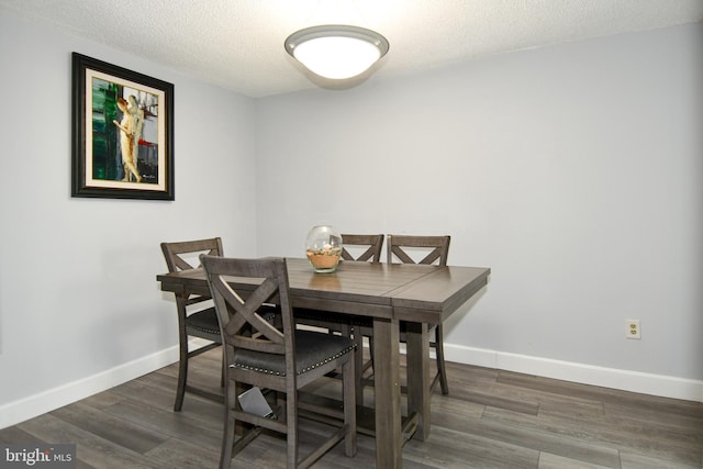 dining space with dark wood-type flooring and a textured ceiling