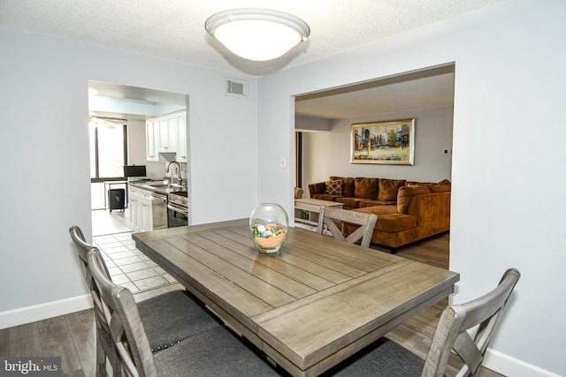 dining room with sink, a textured ceiling, and light wood-type flooring