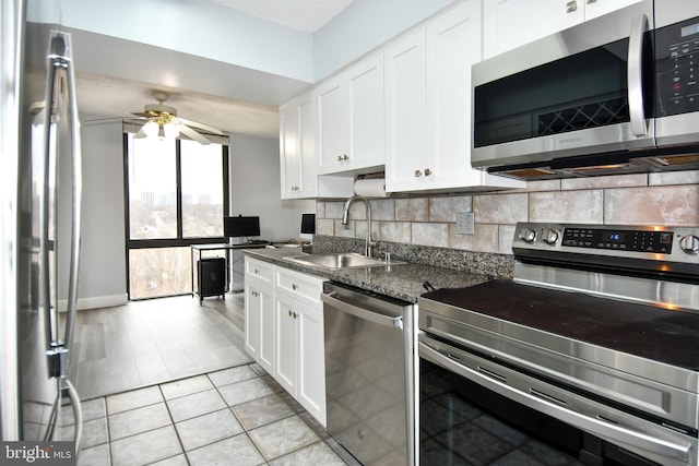 kitchen featuring sink, dark stone countertops, white cabinets, backsplash, and stainless steel appliances