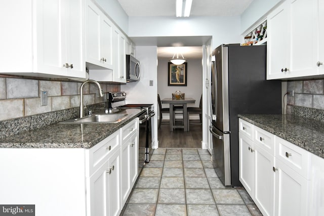 kitchen with dark stone countertops, sink, stainless steel appliances, and white cabinets