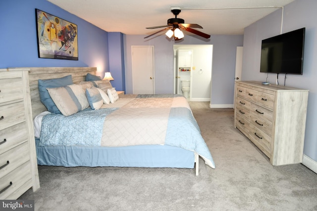 bedroom with connected bathroom, light colored carpet, and ceiling fan