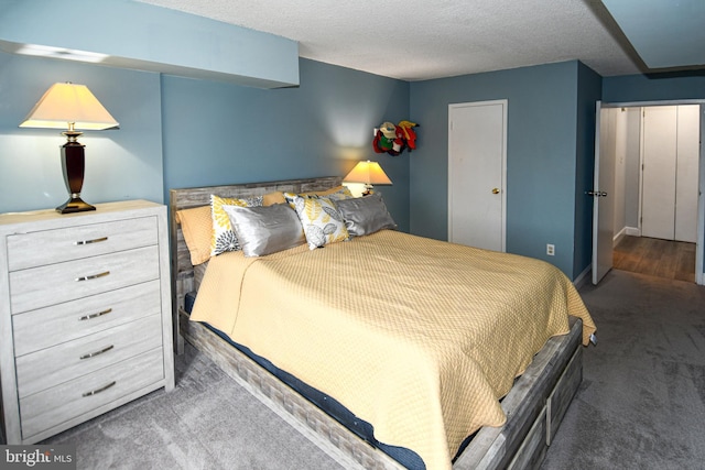 bedroom with dark carpet and a textured ceiling