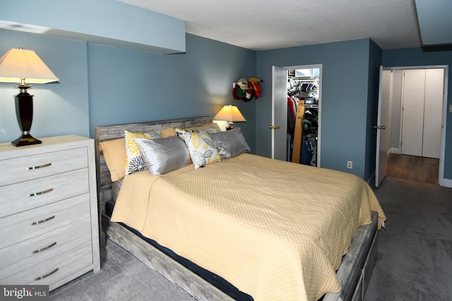 bedroom featuring a spacious closet, dark carpet, and a closet