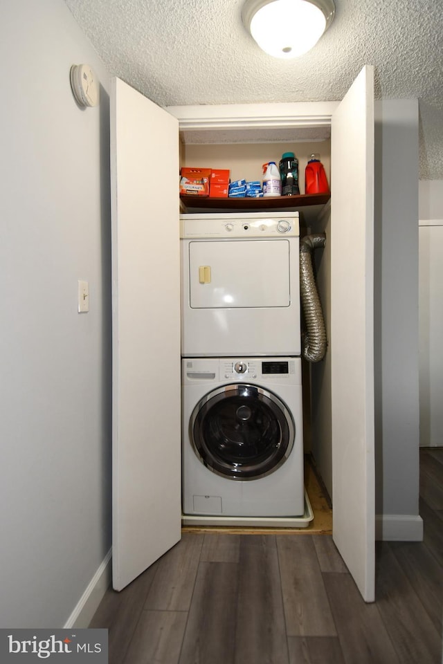 laundry area with stacked washing maching and dryer, dark hardwood / wood-style flooring, and a textured ceiling