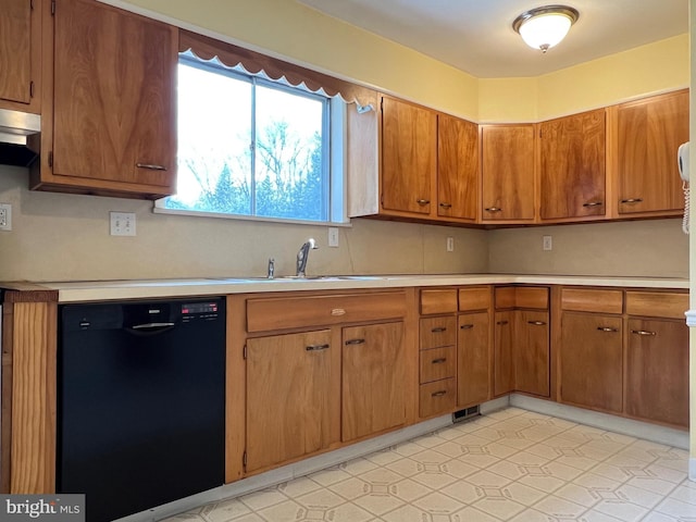 kitchen featuring black dishwasher, brown cabinets, light countertops, under cabinet range hood, and a sink