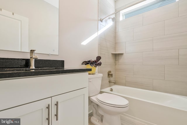 full bathroom featuring tiled shower / bath, vanity, and toilet