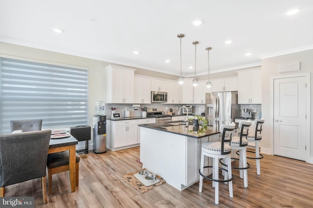 kitchen featuring hanging light fixtures, an island with sink, appliances with stainless steel finishes, and white cabinets