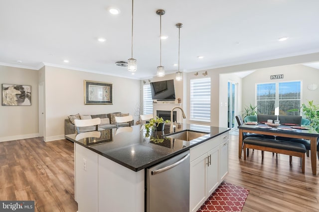 kitchen with pendant lighting, dishwasher, an island with sink, sink, and white cabinets