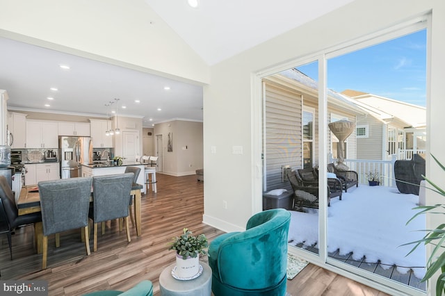 dining space featuring crown molding, lofted ceiling, and light hardwood / wood-style flooring