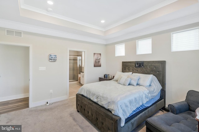 bedroom featuring crown molding, ensuite bath, a tray ceiling, and light carpet