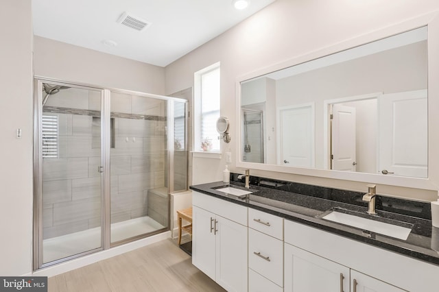 bathroom with a shower with door and vanity