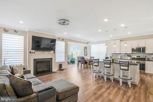 living room with ornamental molding and light wood-type flooring