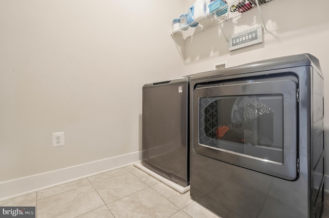 clothes washing area featuring washing machine and clothes dryer and light tile patterned flooring