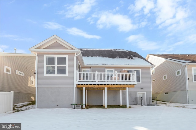 snow covered back of property featuring cooling unit and a wooden deck