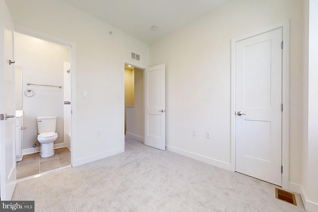 unfurnished bedroom with connected bathroom and light carpet