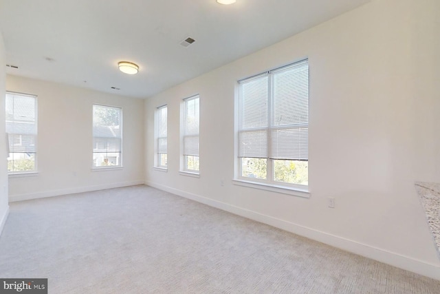 empty room with light colored carpet and a healthy amount of sunlight