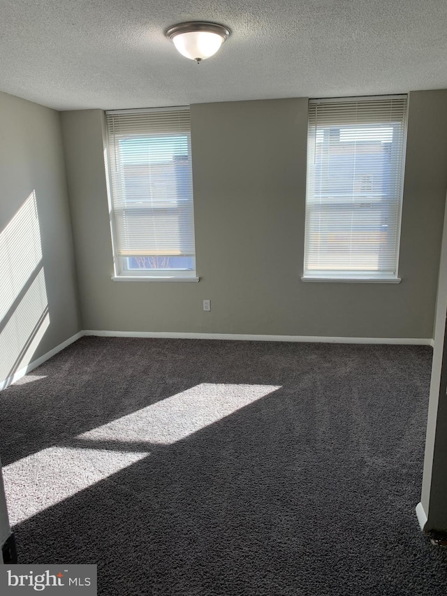 carpeted empty room featuring a textured ceiling