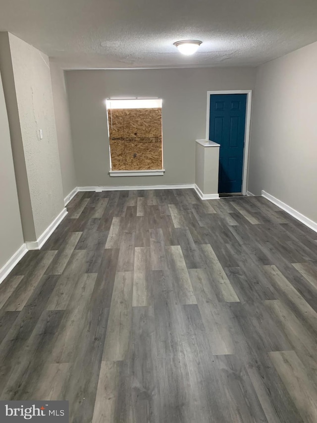 unfurnished room featuring dark wood-type flooring and a textured ceiling