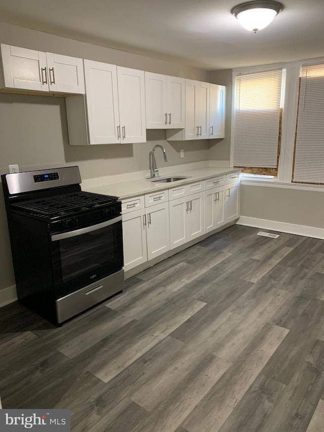 kitchen with stainless steel range with gas cooktop, sink, white cabinets, and dark hardwood / wood-style floors