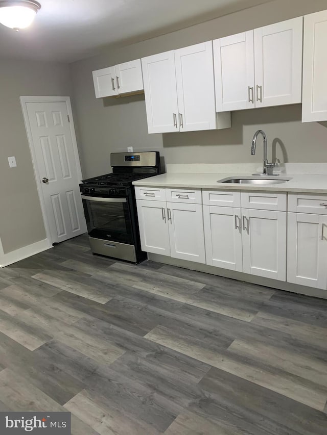 kitchen featuring hardwood / wood-style flooring, white cabinetry, sink, and stainless steel gas range