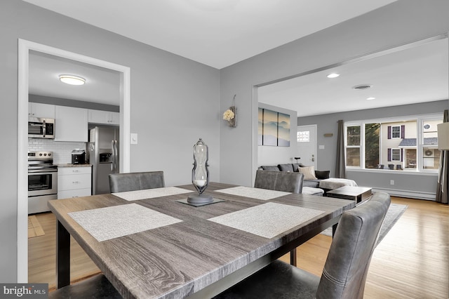 dining room with baseboard heating and light wood-type flooring