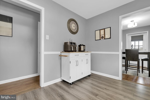 bar with white cabinetry and light wood-type flooring