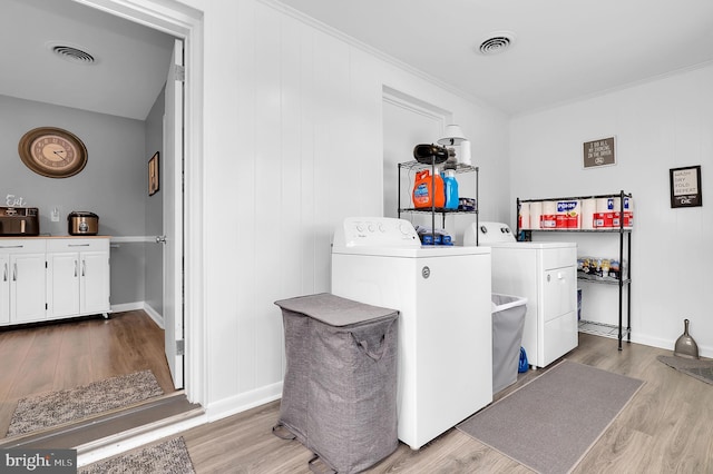 washroom featuring ornamental molding, independent washer and dryer, and light hardwood / wood-style flooring