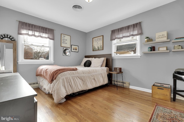 bedroom with multiple windows, a baseboard radiator, and light hardwood / wood-style floors