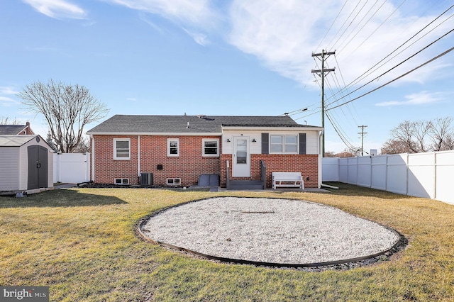 rear view of house with cooling unit, a yard, and a shed