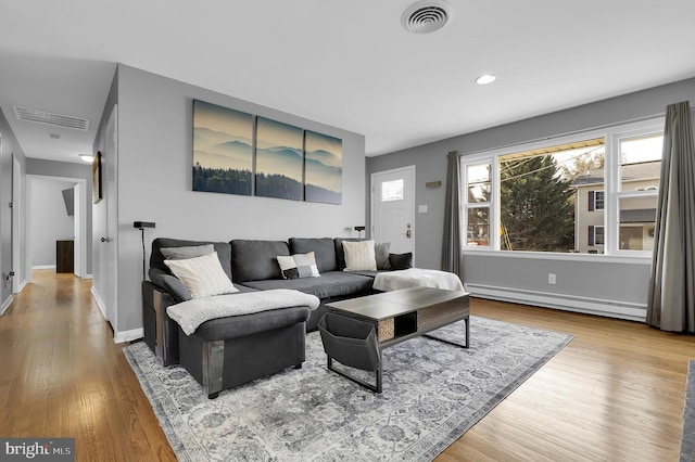 living room with light wood-type flooring and a baseboard heating unit